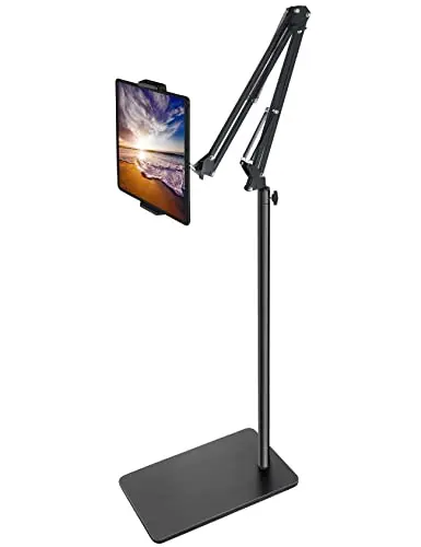 BluuSuuk black tablet floor stand with a heavy weighted base next to a bed.